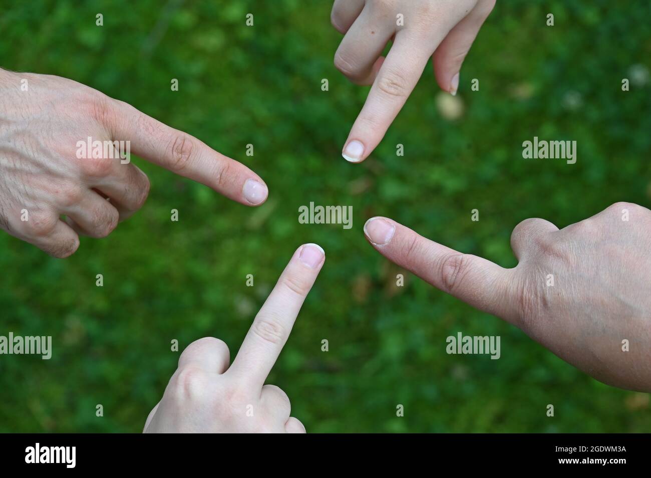 Die ausgestreckten Finger von vier Händen zeigen aufeinander Stockfoto