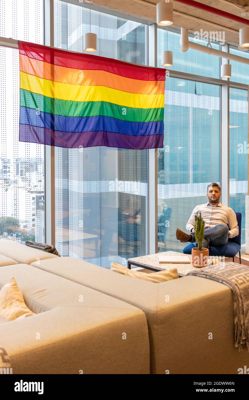 Ein hübscher Mann in legerem Kleid, der die Flagge der LGBT-Gemeinschaft in Erwägung zieht Stockfoto