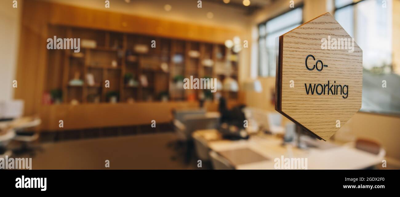 Co-Working Schreiben auf Holzplatte über einer Glaswand. Offener Bürobereich für Coworking. Stockfoto