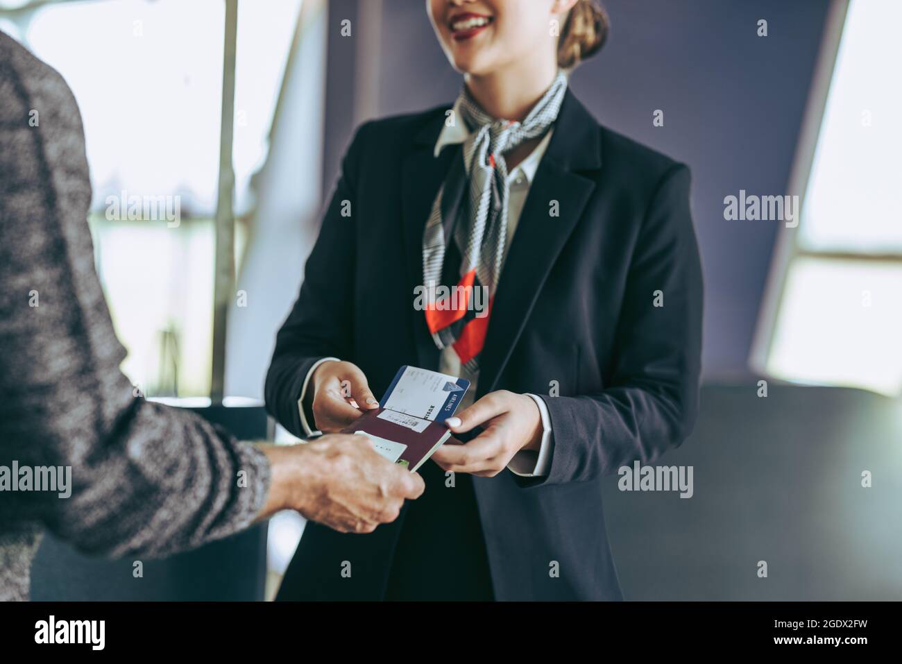 Eine kurze Aufnahme des Flugbegleiters mit Touristen am Check-in-Schalter am Flughafen. Bodenpersonal überprüft die Bordkarte des Reisenden am Flughafen. Stockfoto