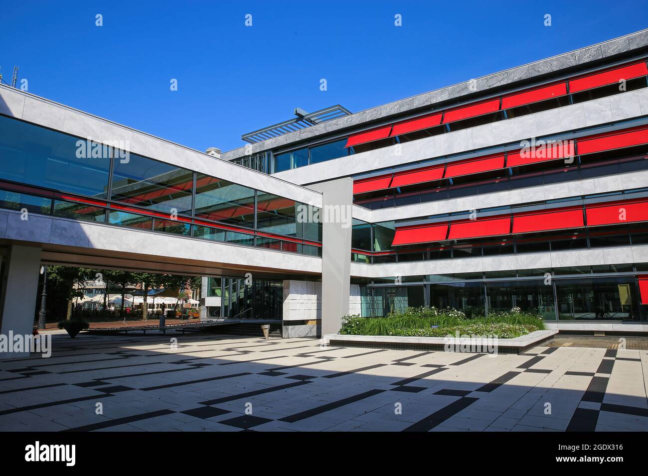 Arnhem (Stadhuis), Niederlande - Juli 9. 2021: Blick auf den großen Innenhof des modernen Rathauses mit reflektierender Glasfassade und roten Markisen Stockfoto