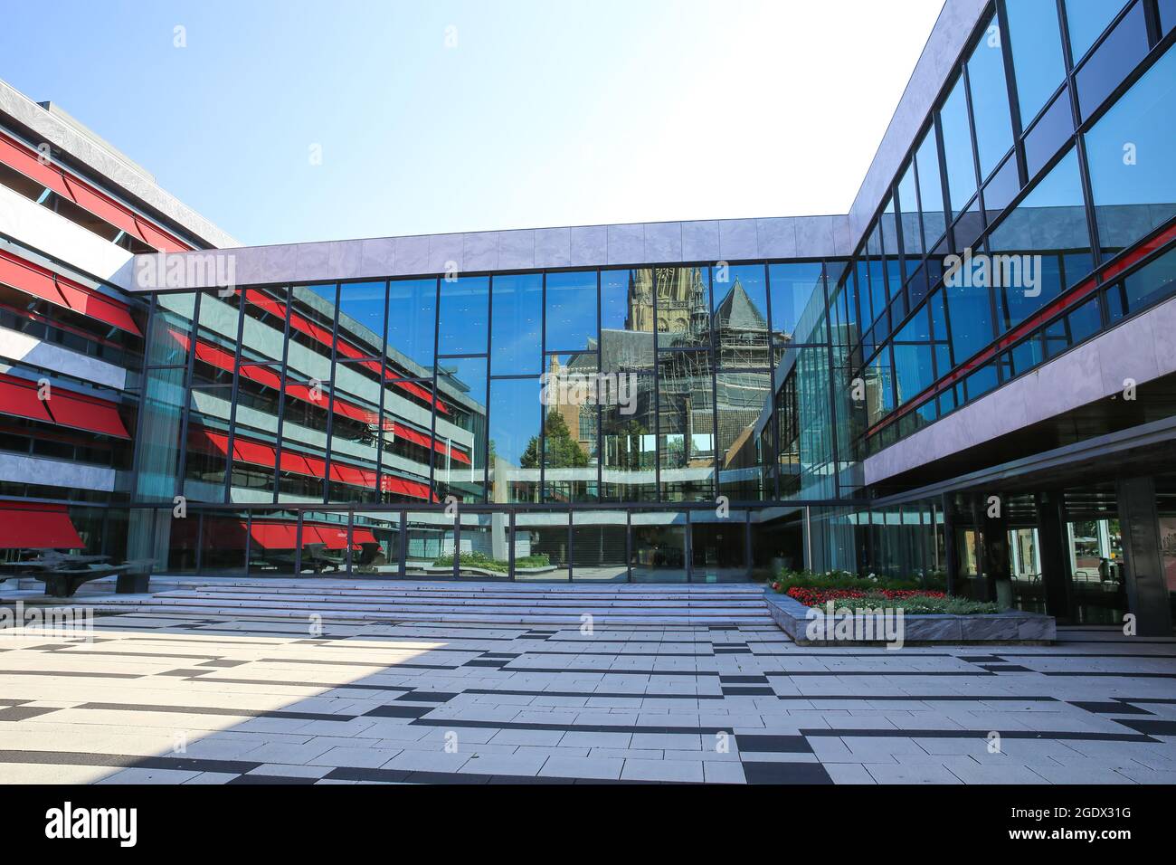 Arnhem (Stadhuis), Niederlande - Juli 9. 2021: Blick auf den großen Innenhof des modernen Rathauses mit reflektierender Glasfassade und roten Markisen Stockfoto