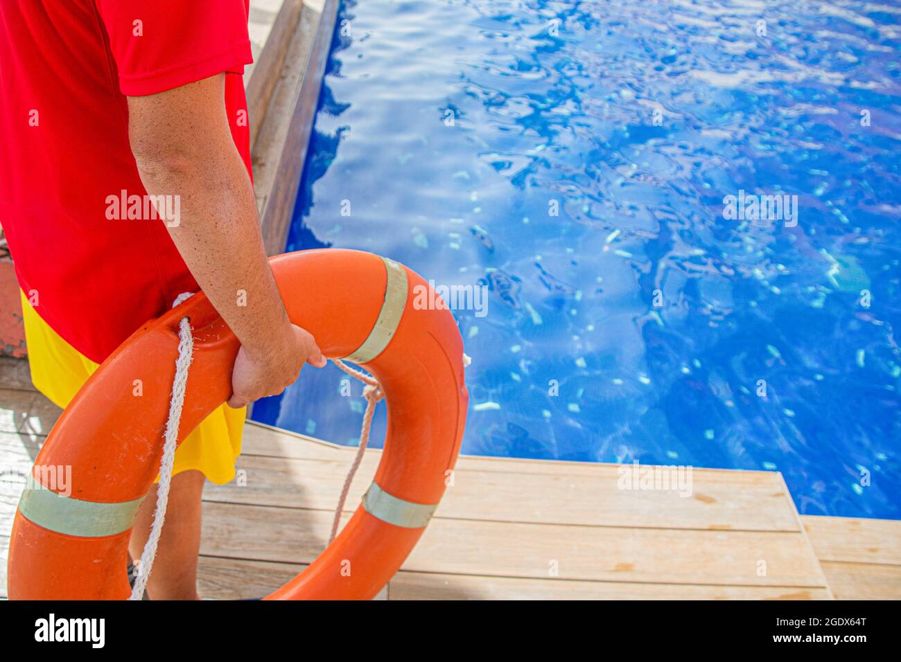 Nahaufnahme der Hand eines Rettungsschwimmens, der einen Rettungsring ergattet und einen Swimmingpool beobachtet - Konzept des Rettungsschwimmens bei der Arbeit Stockfoto