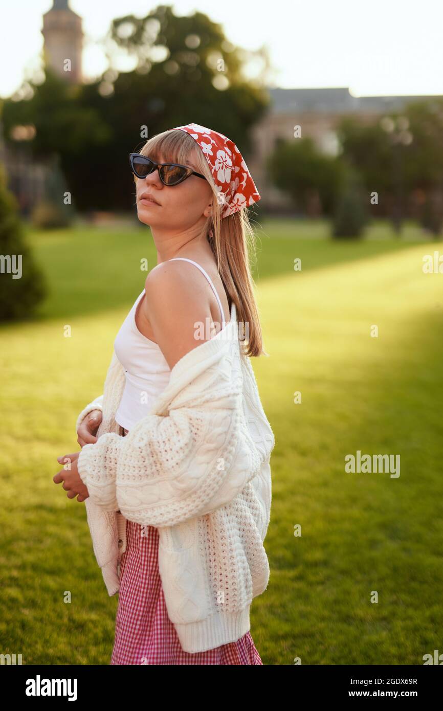 Junge attraktive Frau Porträt in weißem Top, Pullover und Tuch im Sonnenuntergang im Sommer. Mode gestylt teen Mädchen. Urlaub in der Natur, Sommer oder Reisekonzept an sonnigen Tagen. Hochwertige Bilder Stockfoto