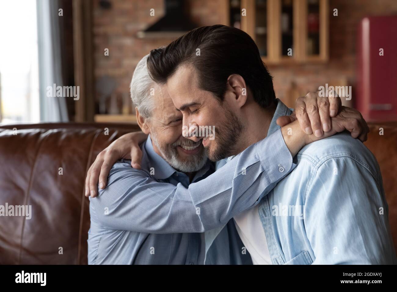 Liebevolle reife Vater umarmt erwachsenen erwachsenen Sohn Stockfoto