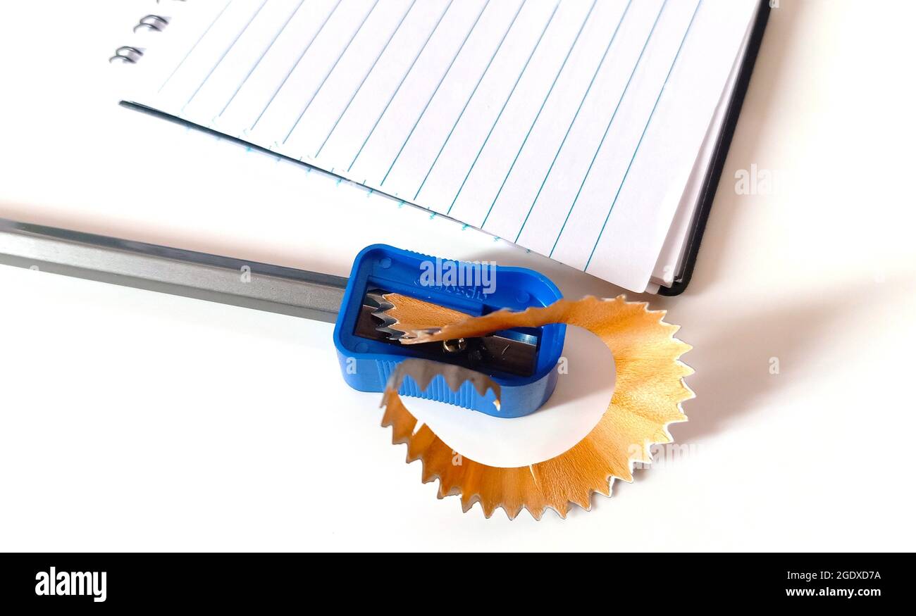 Ein leeres offenes Notizbuch mit Bleistift und Spitzer auf einem weißen Tisch mit einem Kopierplatz Stockfoto