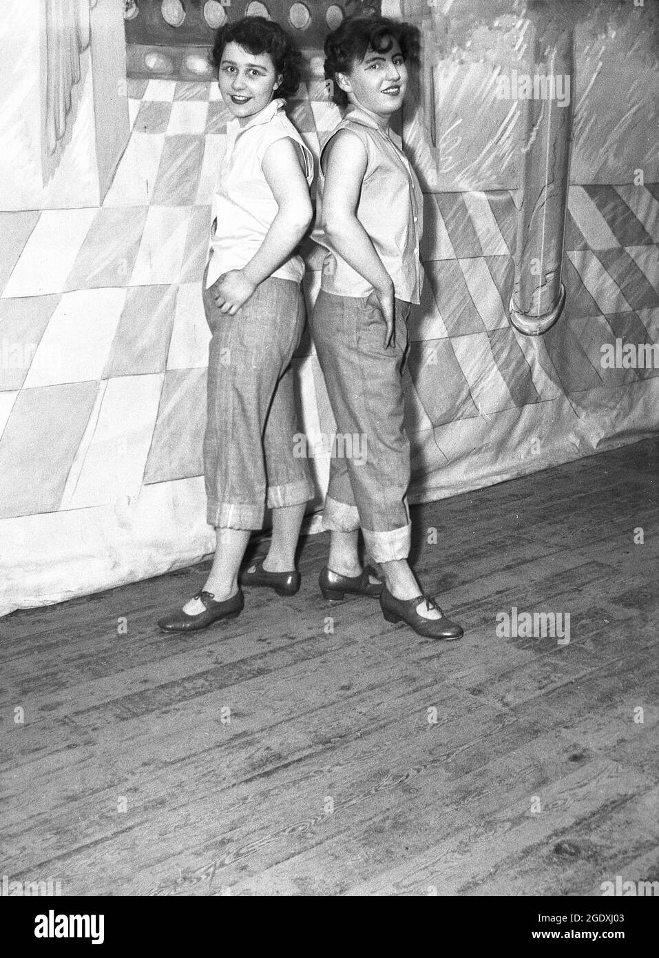 1957, historische, zwei junge weibliche Performer in ihren Kostümen - Jeans tauchten bei den ankes auf und ärmellose Blusen - erschienen in der Pantomine Aladdin, einer Geschichte, die auf einer mittelöstlichen Volksgeschichte basiert und auf der Bühne für ihr Foto stand, England, Großbritannien. Jeans mit Handschellen oder aufgerollten Hosen wurden in Großbritannien zu Beginn des Rock and Roll modisch, als Rockabilly populär wurde. Stockfoto