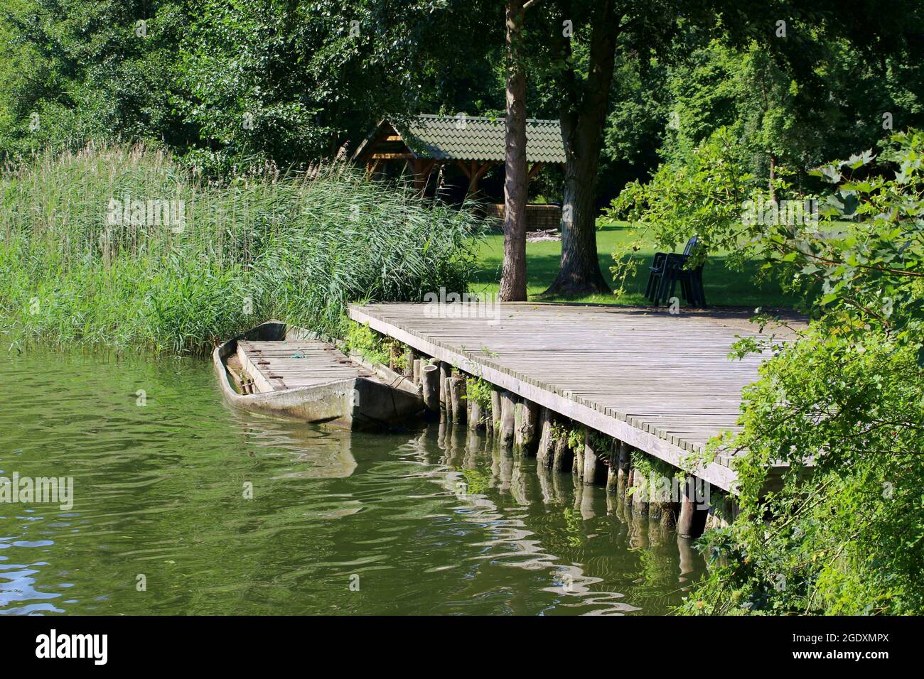 Kleines Boot auf einem Dock umgeben von Schilf, Gras und Wäldern in der Mecklenburgischen Seenplatte Stockfoto