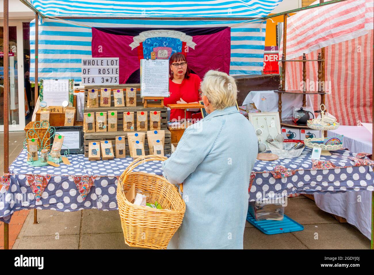 Eine Frau, die mit einem Kunden auf einem britischen Bauernmarkt spricht und mehrere Sorten von Rosie Loose REA verkauft Stockfoto
