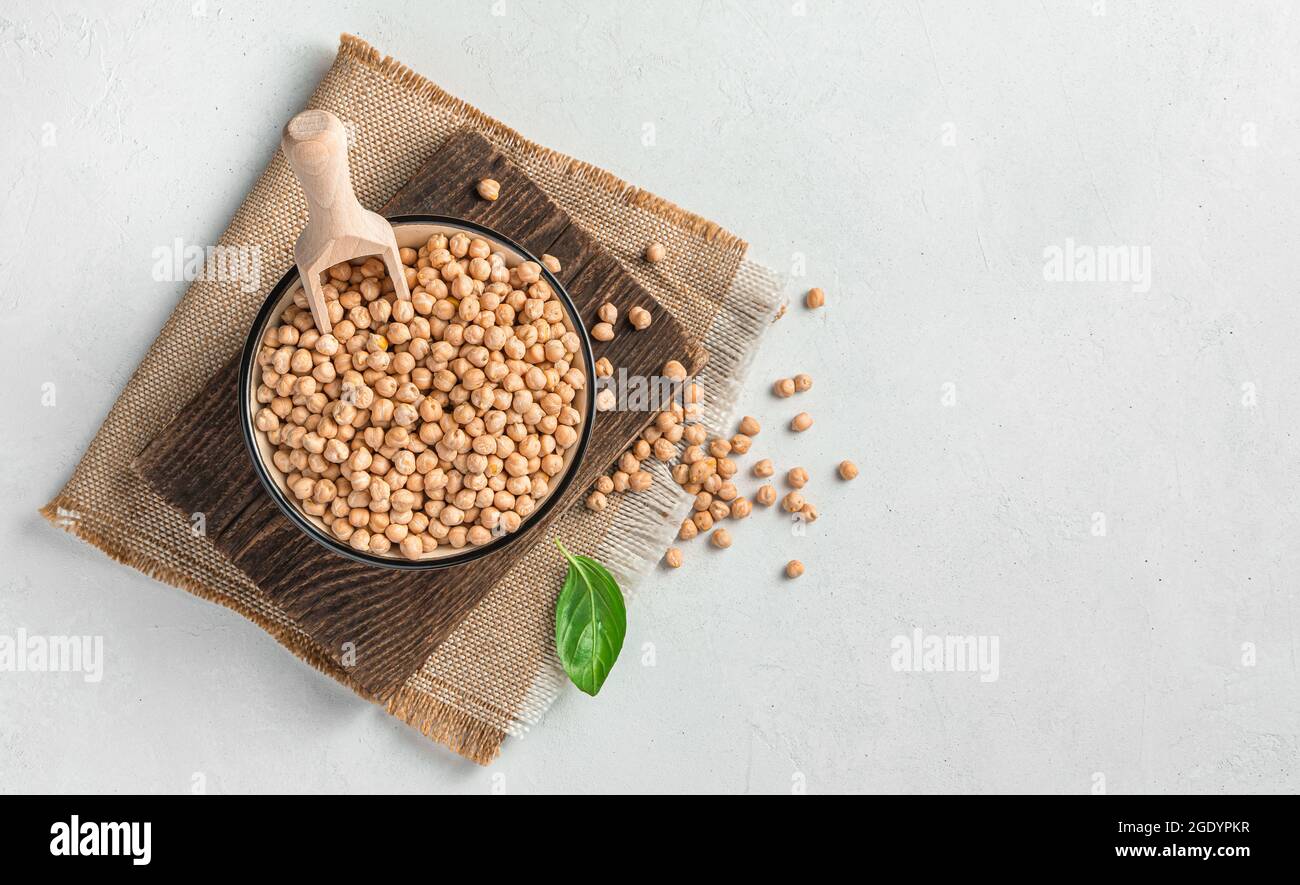 Kichererbsen in einer Schüssel mit einer Holzlöffel auf grauem Hintergrund. Stockfoto