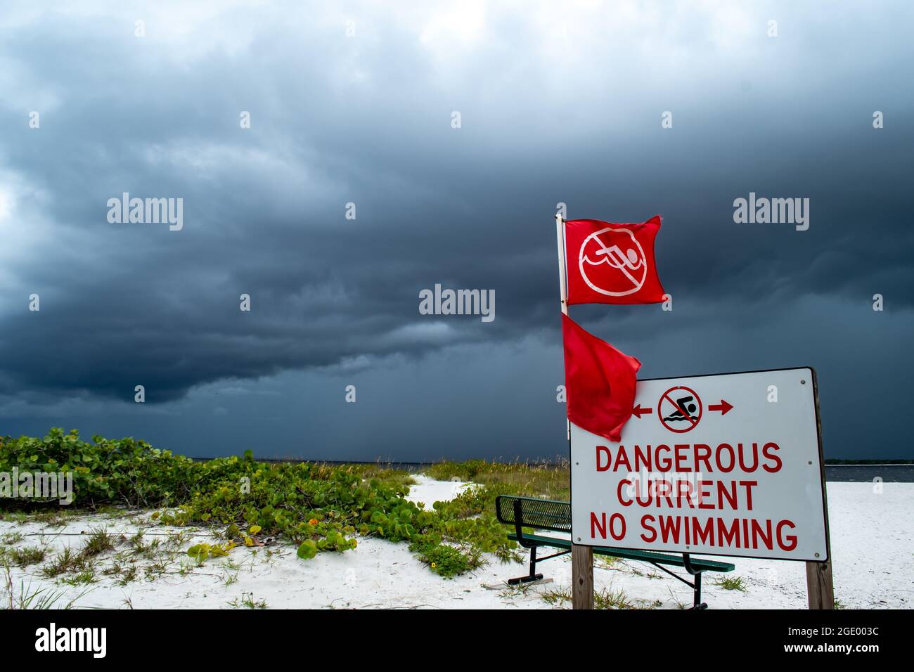 Warnschilder am Strand mit roten Flaggen; Port Boca Grande Leuchtturm und Museum, Gasparilla Island als ein tropischer Sturm mit schwarzen Wolken versammeln Stockfoto