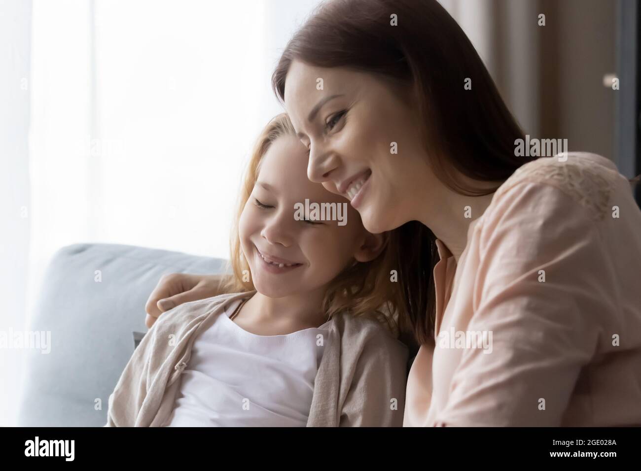 Lächelnd liebende Mutter und kleine Tochter entspannen kuscheln Stockfoto