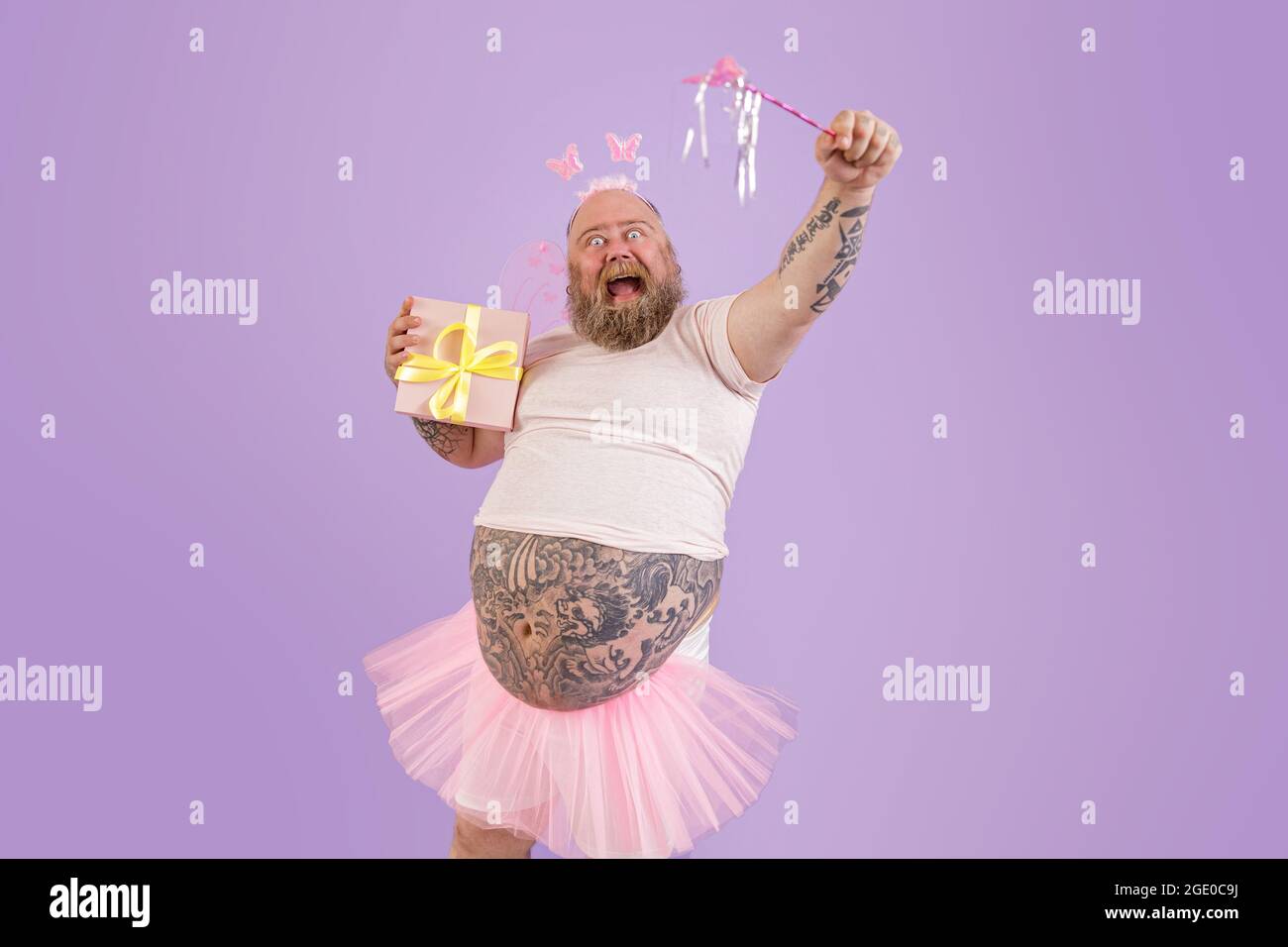 Aufgeregt Mann mit Übergewicht in Fee Kostüm hält Zauberstab und  präsentieren auf lila Hintergrund Stockfotografie - Alamy