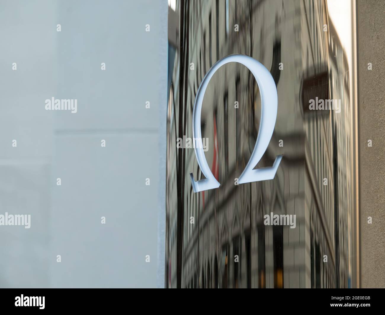 ZÜRICH, SCHWEIZ - 30. NOVEMBER 2019: Das Logo der Marke Omega auf reflektierendem Hintergrund an der Wand des Stores in Zürich mit einer Reflexion Stockfoto