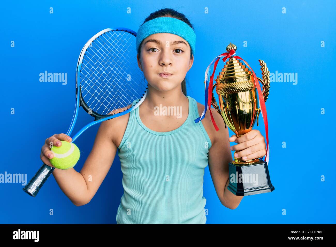 Schöne Brünette kleines Mädchen spielen Tennis mit Trophäe Puffing Wangen  mit lustigen Gesicht. Mund mit Luft aufgeblasen, Luft fangen  Stockfotografie - Alamy