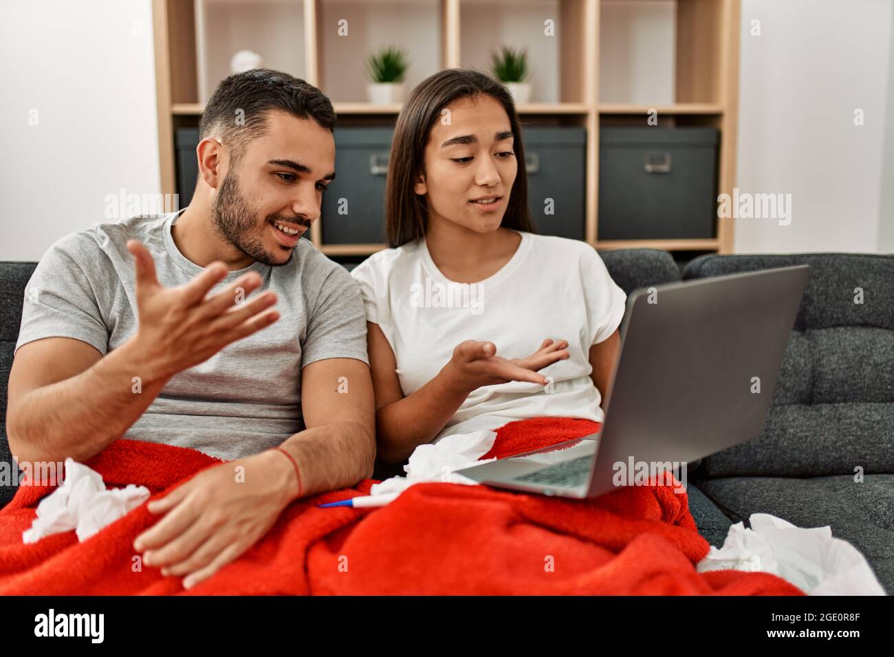 Junge lateinamerikanische kranke Paare, die zu Hause eine medizinische Fernsulation mit einem Laptop haben. Stockfoto