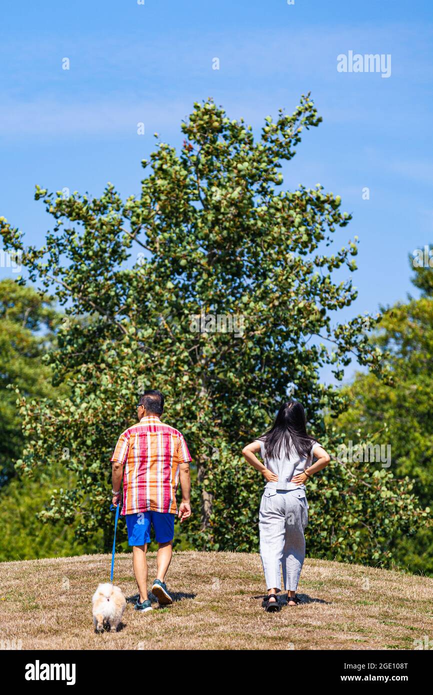 Asiatisches Paar, das in Steveston, British Columbia, Kanada, mit seinem Hund unterwegs ist Stockfoto