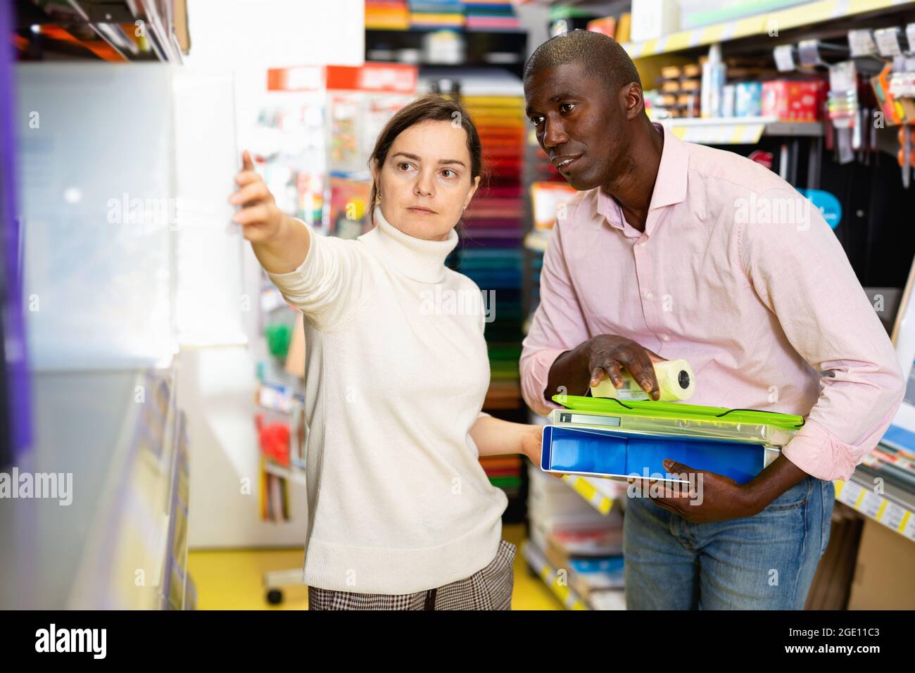 Junges Paar zeigt während des Einkaufens auf Regale mit Bürobedarf im Schreibwarenladen Stockfoto