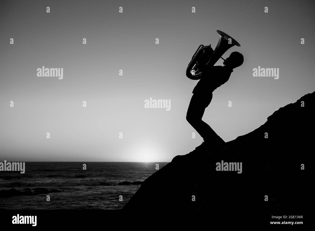 Silhouette eines Musikers mit einer Tuba am Meer. Schwarzweiß-Foto. Stockfoto
