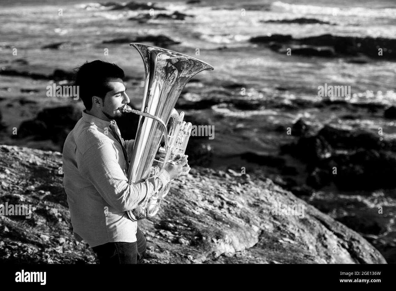 Ein Mann mit einer Tuba am Meer. Schwarzweiß-Foto. Stockfoto