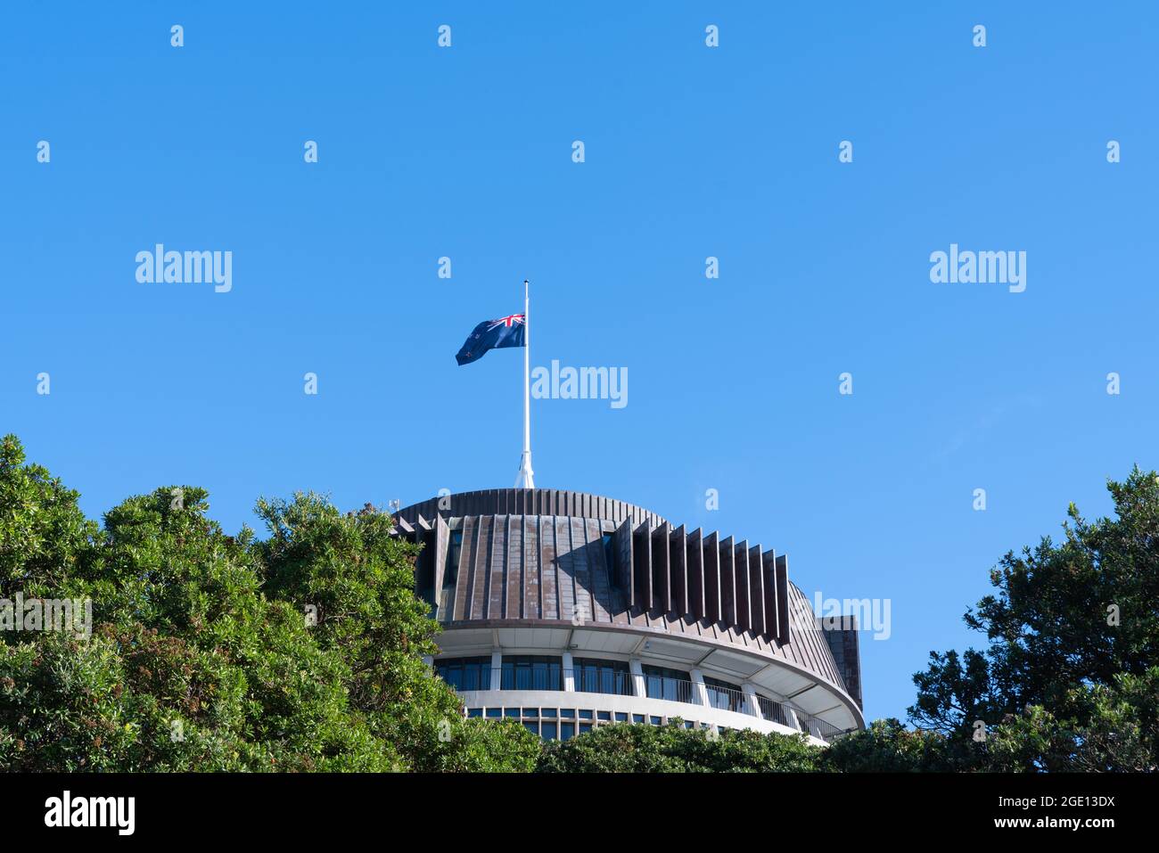 Die neuseeländische Flagge, die über dem Dach des Regierungsgebäudes fliegt, ist ein kreisförmiges Wahrzeichen, das als Beehive in Wellington, Neuseeland, bekannt ist. Stockfoto