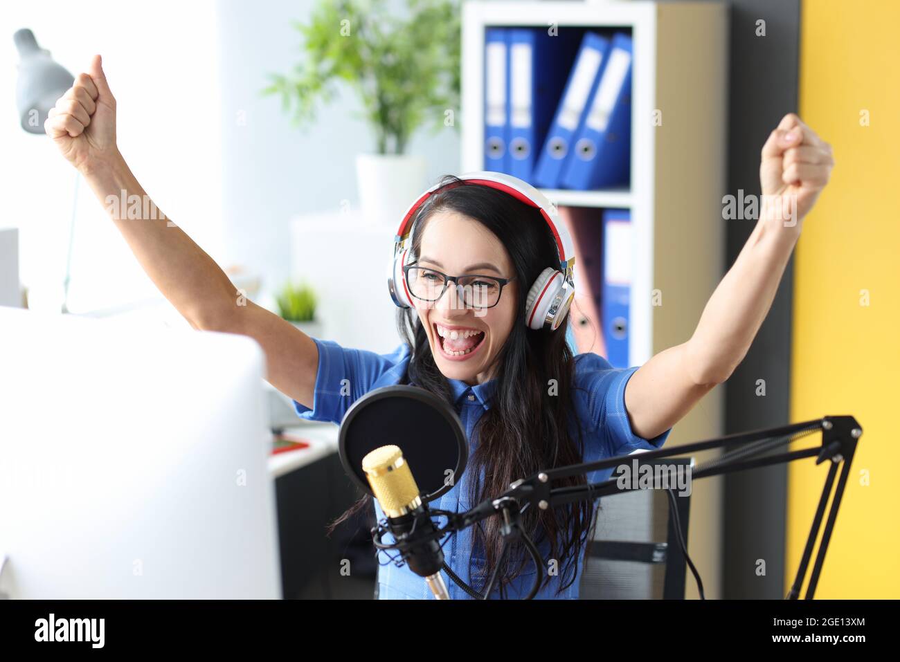 Lächelnde Frau in Kopfhörern jubelt vor dem Mikrofon beim Radiosender Stockfoto