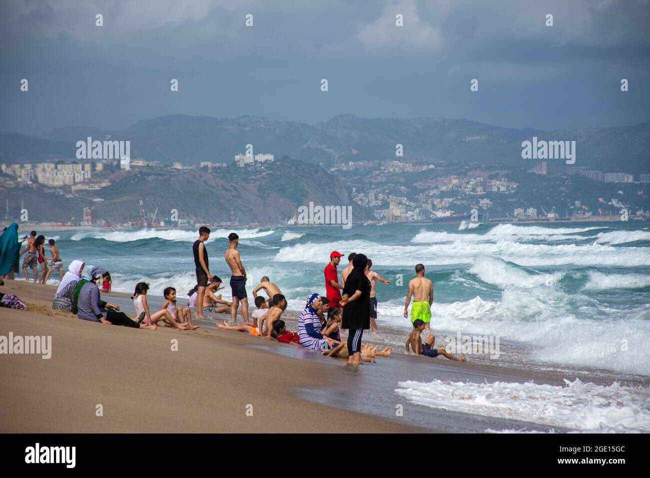 Gruppe von Menschen, die im Meeresschaum am Strand von Jeanne D'Arc, Skikda, Algerien, stehen. Stockfoto