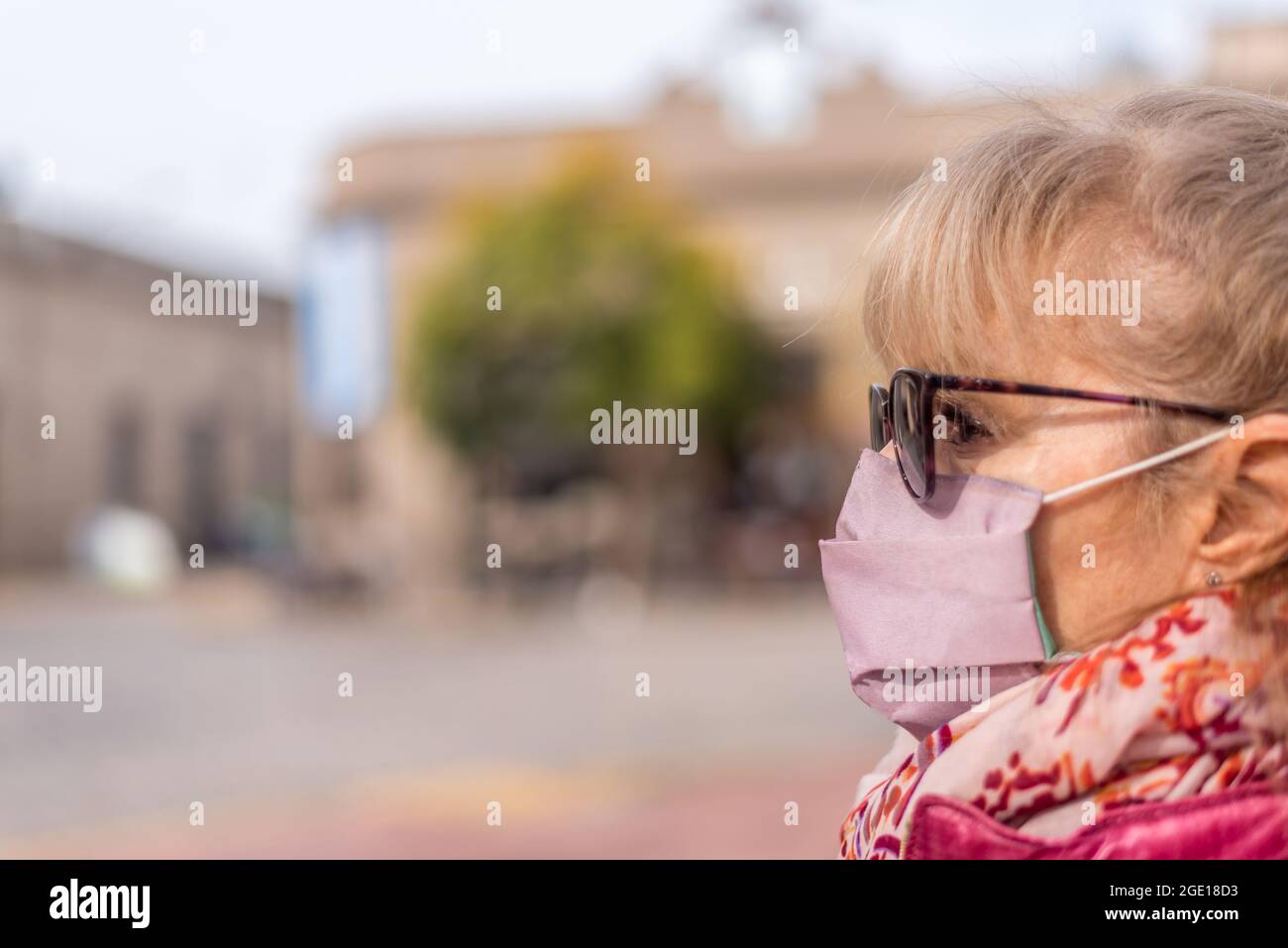 Nahansicht einer erwachsenen Frau, die draußen eine schützende Gesichtsmaske und eine Sonnenbrille verwendet. Selektiver Fokus. Stockfoto