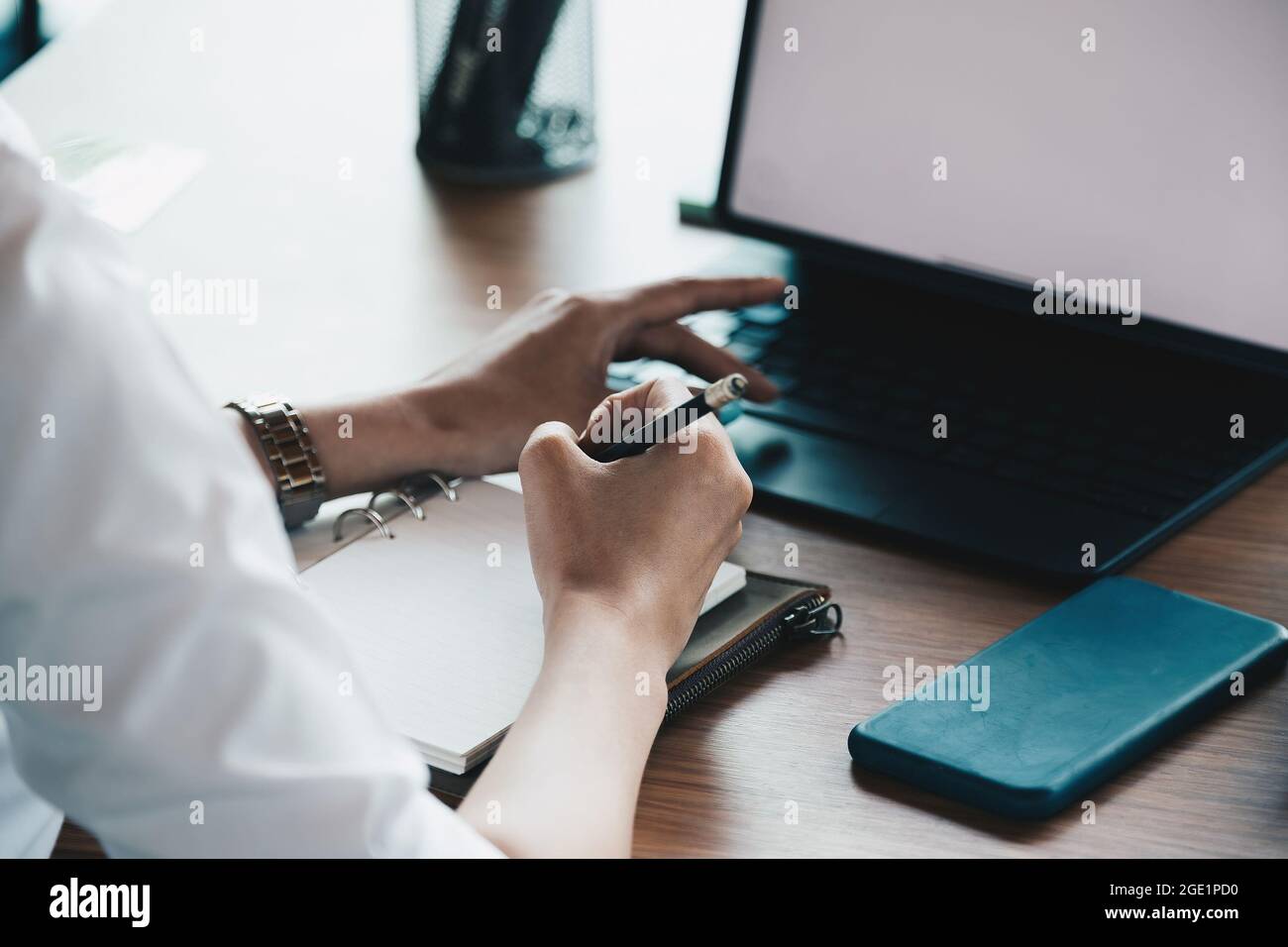 Eine Frau, die sich mit einem Laptop am Tischbüro Notizen gemacht hat Stockfoto