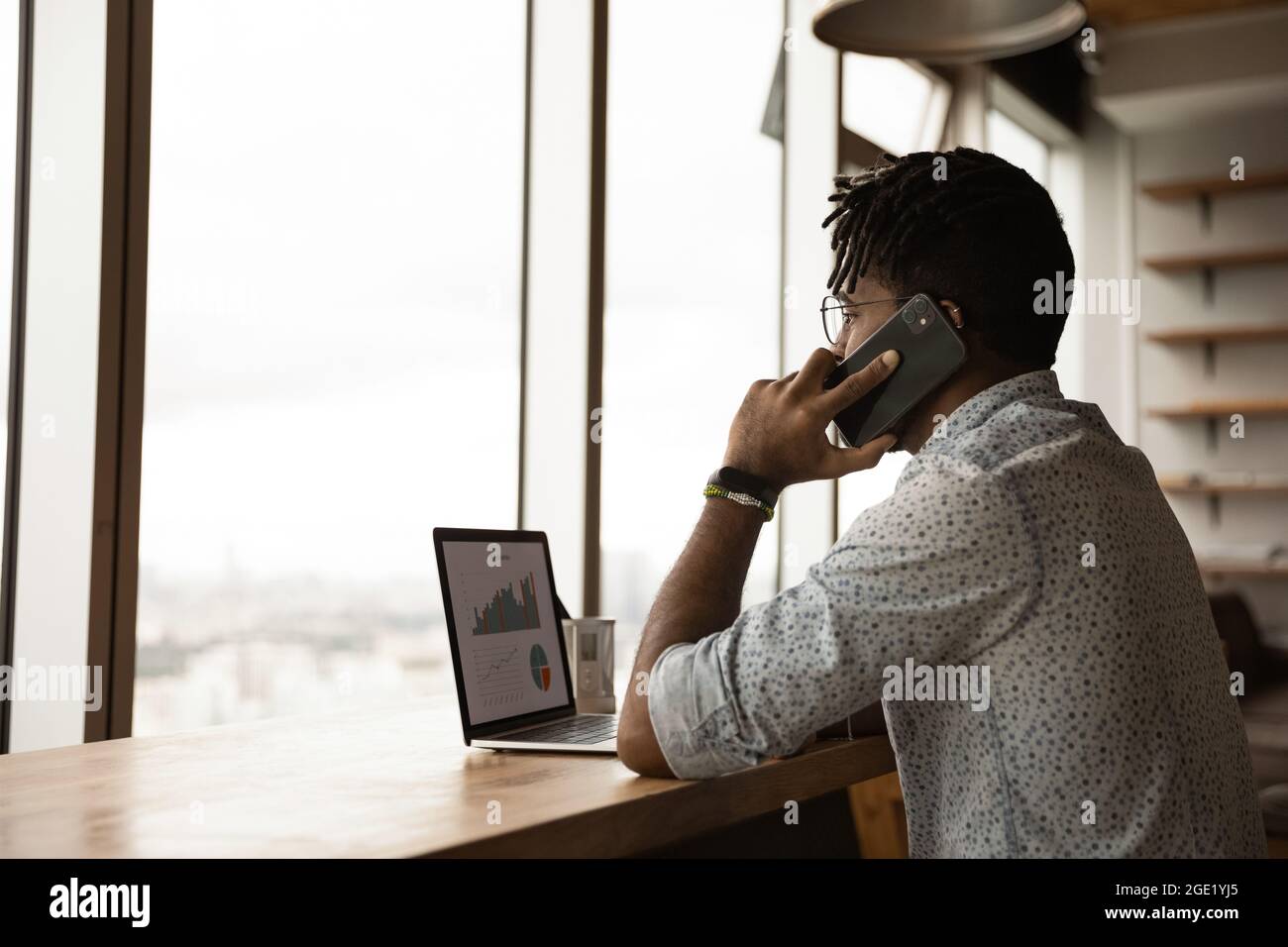 Afrikanischer Unternehmer, der am Telefon spricht, diskutiere mit den Verkaufsstatistiken von Kollegen Stockfoto