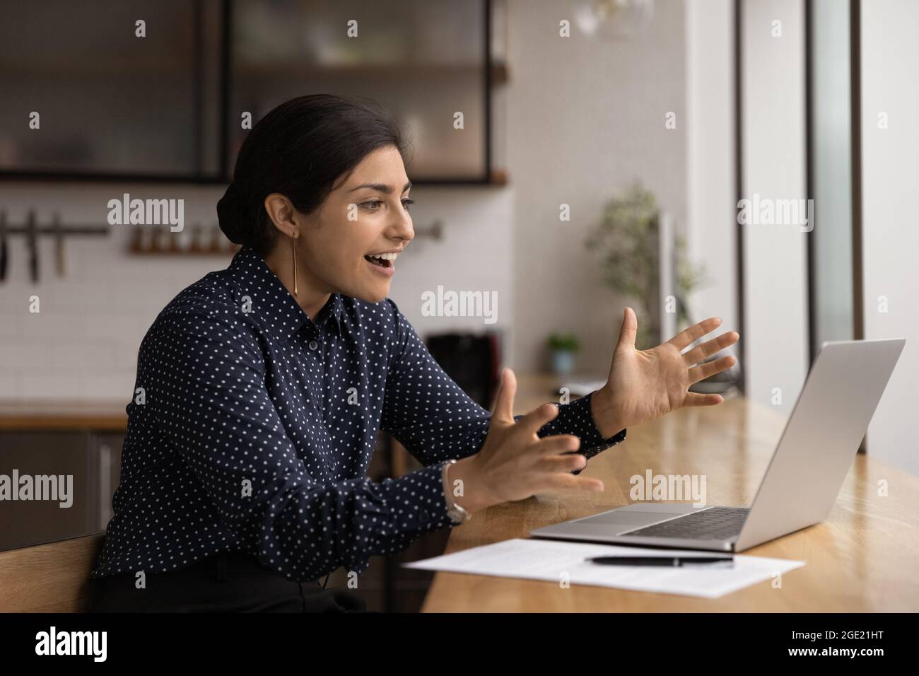 Die indische Frau schaut auf den Laptop und fühlt sich von den guten Nachrichten überrascht Stockfoto