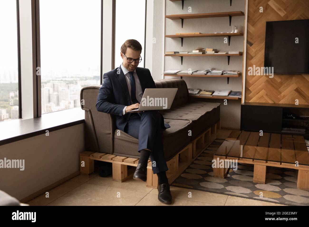 Ein Geschäftsmann im Anzug sitzt im Büro und schreibt auf dem Laptop Stockfoto