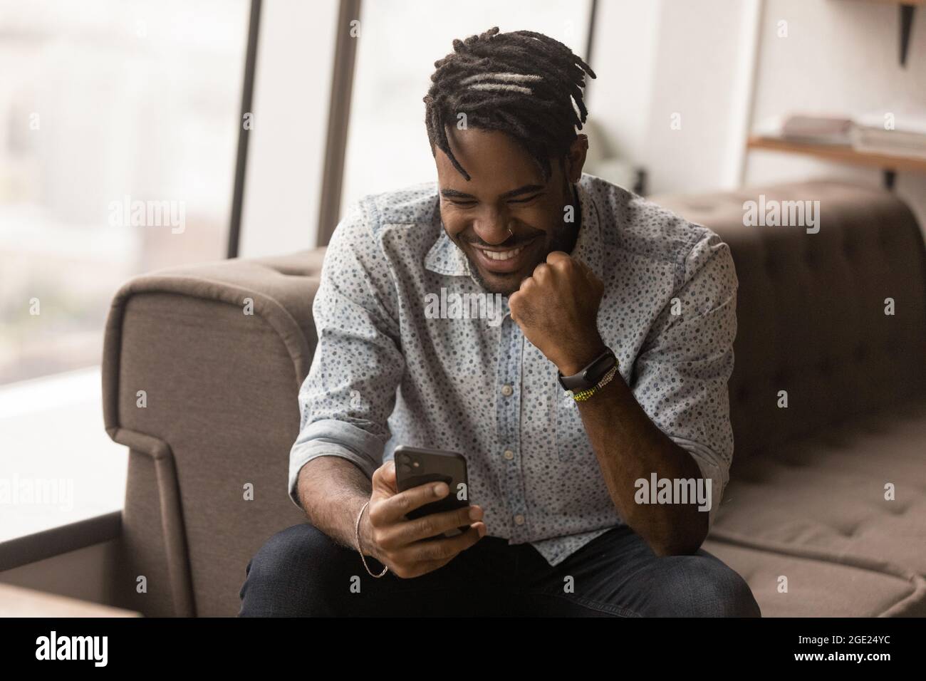 Afrikanischer Kerl lesen gute Nachrichten auf dem Smartphone fühlt sich überglücklich Stockfoto