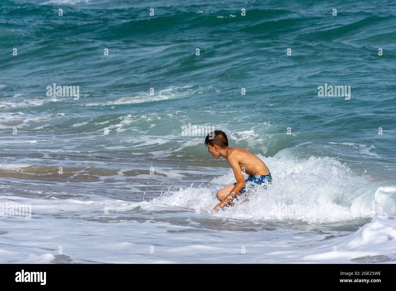 : junger arabischer Junge, der im Meeresschaum am Strand von Jeanne D'Arc, Skikda, Algerien, spielt. Stockfoto