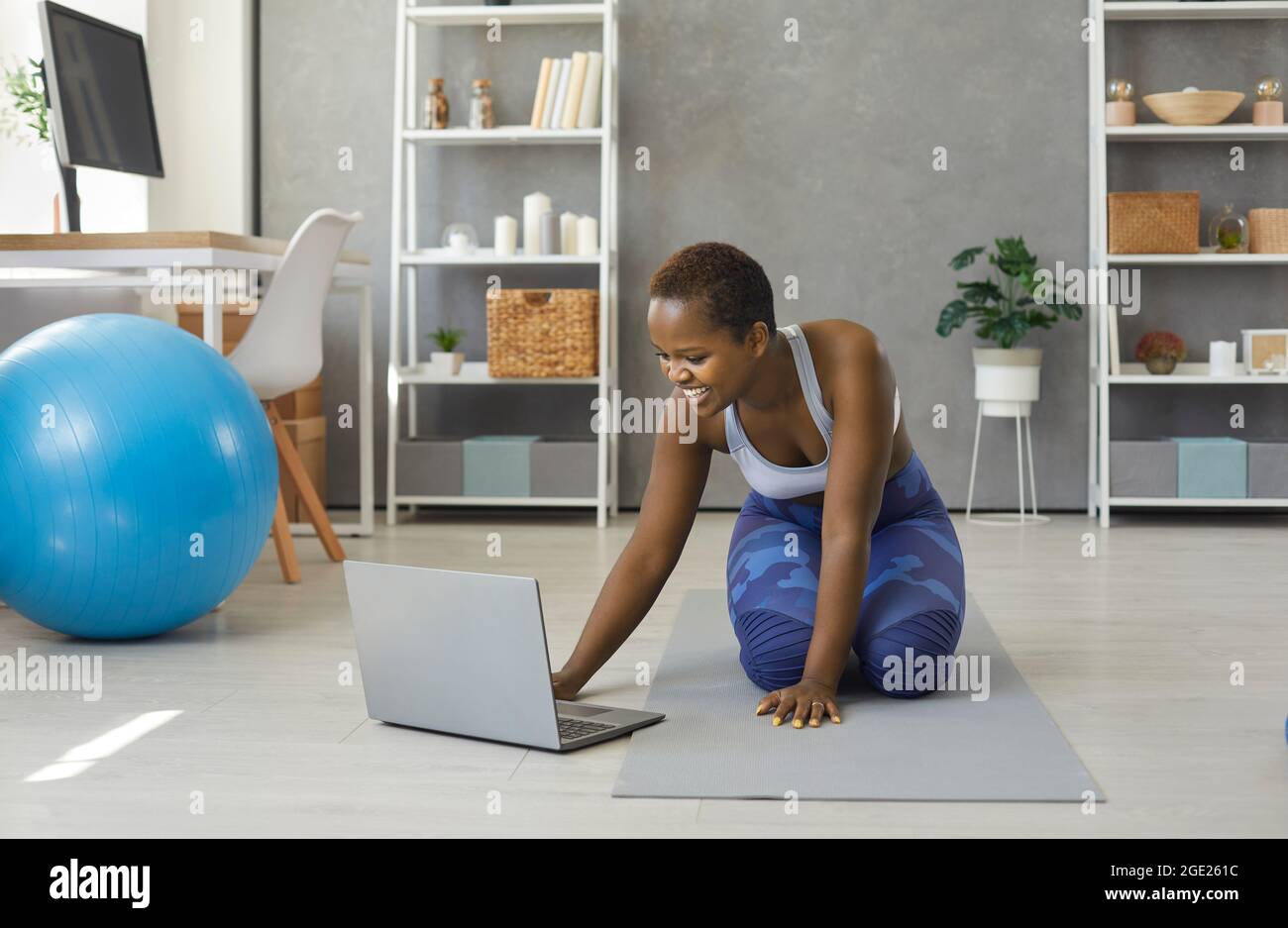 Glückliche junge afroamerikanische Frau schaltet Sporttraining Video-Lektion auf Laptop. Stockfoto