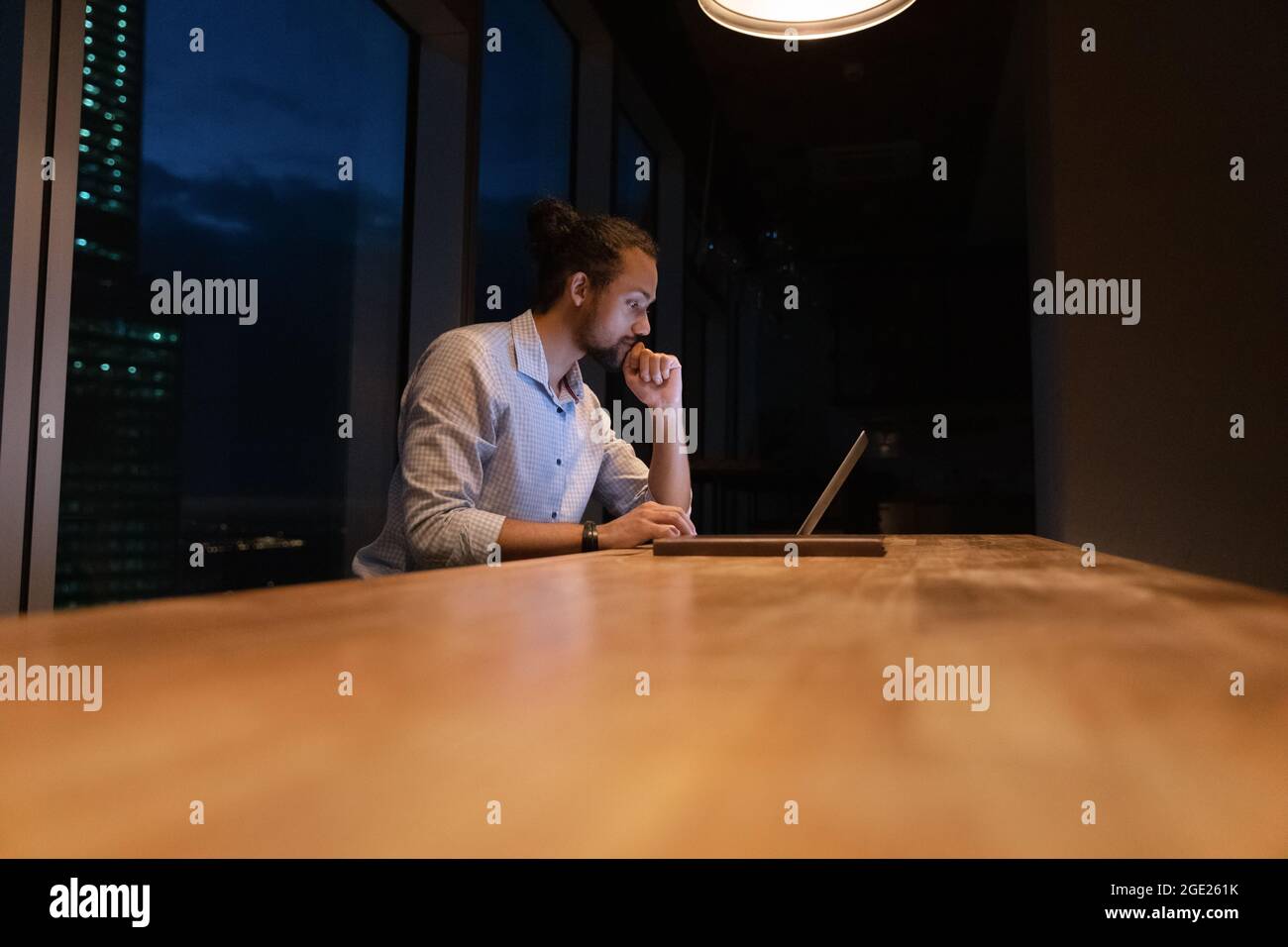 Am Arbeitsplatz sitzen afrikanische Mitarbeiter bis spät in die Nacht auf dem Laptop Stockfoto