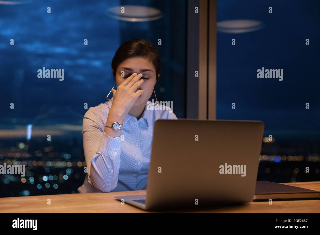 Müde indische Büroangestellte arbeiten spät mit einem Laptop im Büro Stockfoto