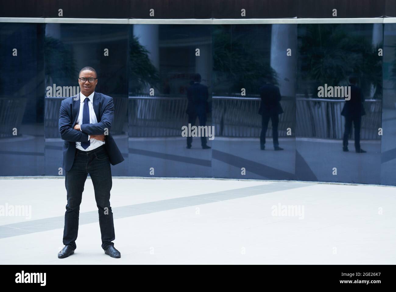 Porträt eines selbstbewussten Unternehmers, der im Freien steht, die Arme kreuzt und die Kamera anschaut Stockfoto