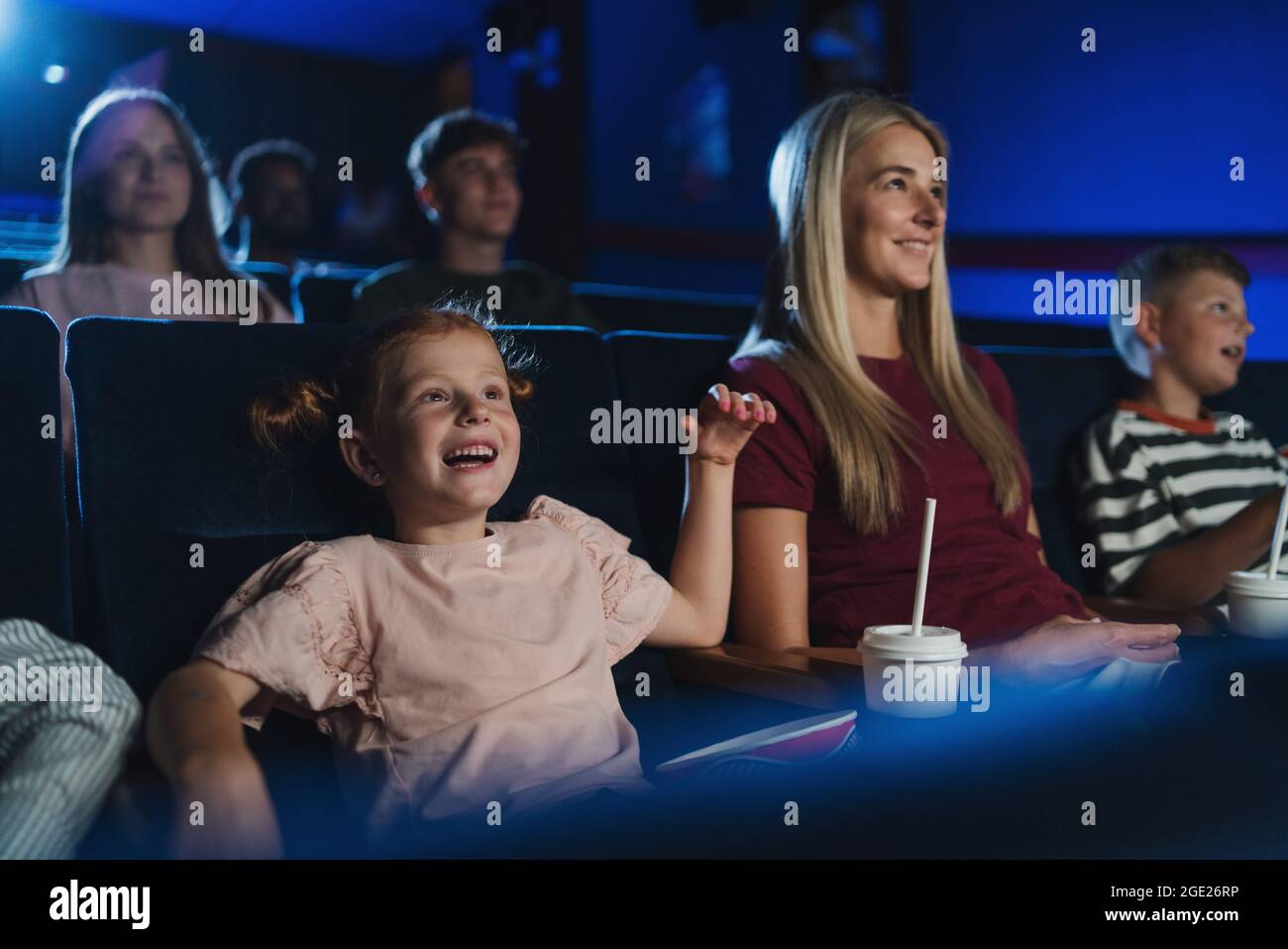 Mutter mit glücklichen kleinen Kindern im Kino, beim Film. Stockfoto