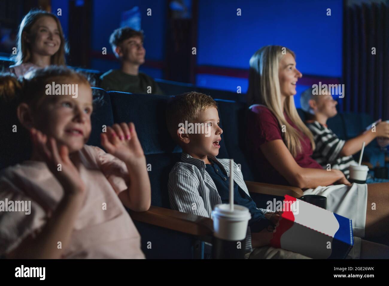 Mutter mit glücklichen kleinen Kindern im Kino, beim Film. Stockfoto