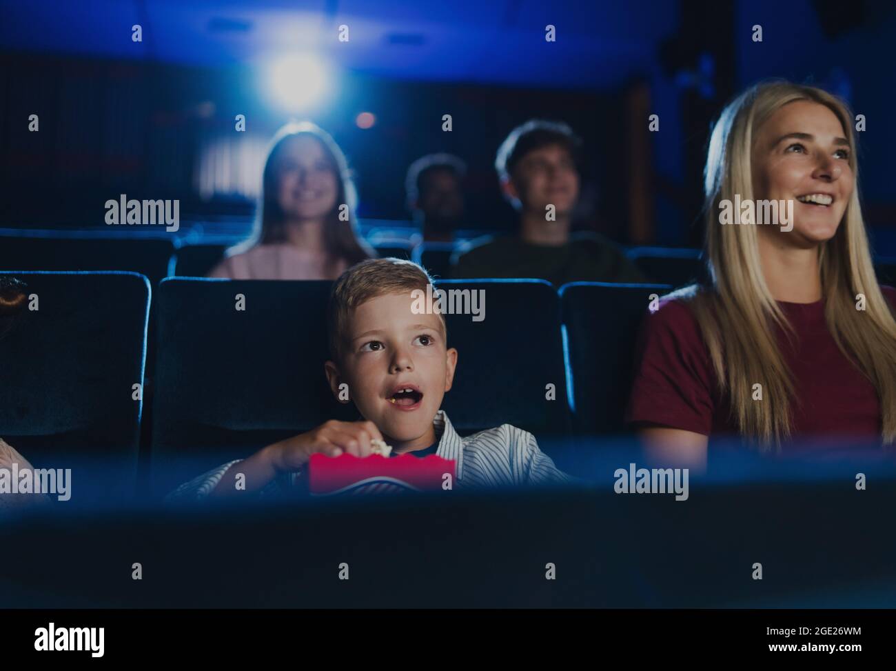 Mutter mit glücklichen kleinen Kindern im Kino, beim Film. Stockfoto