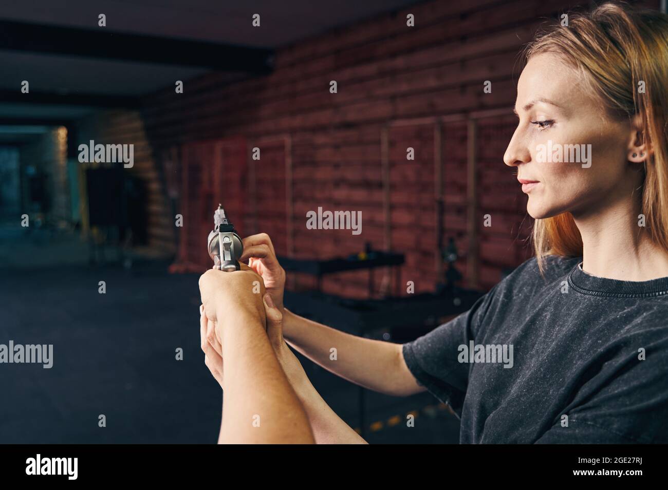 Anfänger lernen, eine Waffe zu handhaben, unterstützt von einem Instruktor Stockfoto