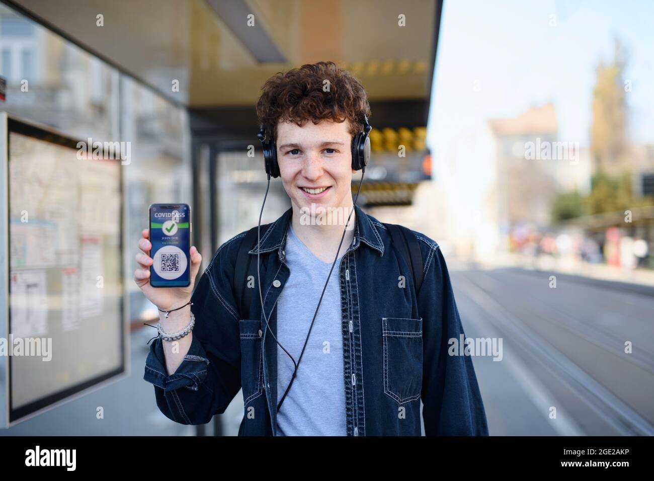 Porträt eines jungen Mannes, der im Freien in der Stadt steht, zeigt covid Pass auf dem Smartphone. Stockfoto