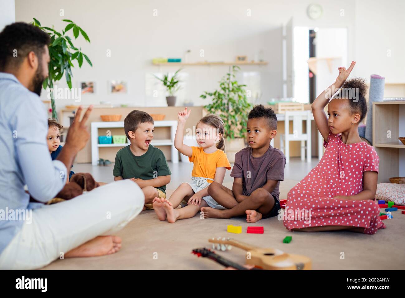 Gruppe von kleinen Kindergartenkindern, die im Klassenzimmer auf dem Boden sitzen. Stockfoto