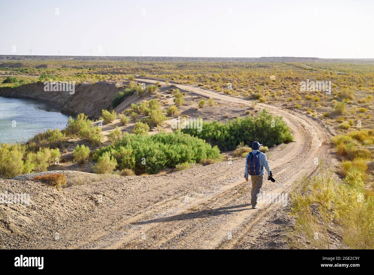 ein asiatischer Fotograf, der in der Wüste gobi auf einer unbefestigten Straße unterwegs ist und die Landschaft bei Sonnenuntergang betrachtet Stockfoto