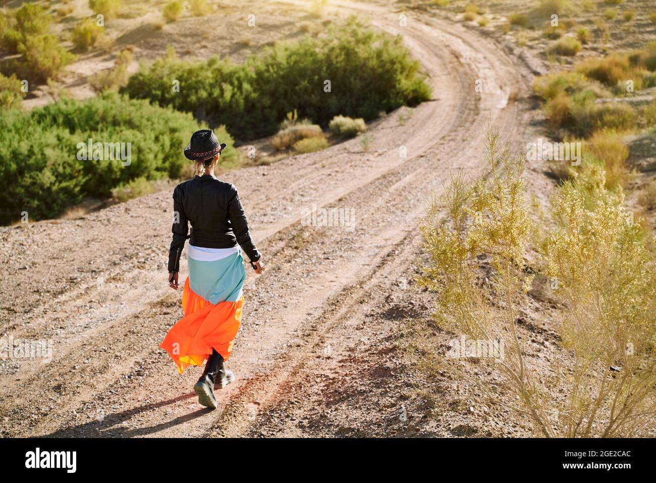Rückansicht einer wunderschönen asiatischen Frau, die auf einer unbefestigten Straße in der wüste gobi unterwegs ist Stockfoto