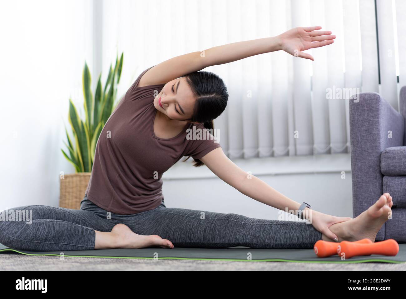 Ein ruhiges Mädchen, das ihren ganzen Körper nach dem Training mit der Spitze eines Beins ausdehnt. Stockfoto
