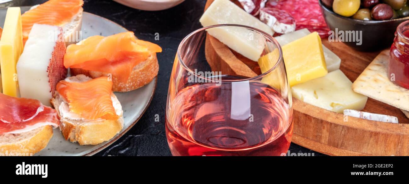 Rosenwein mit Käse, Lachsbrote und Olivenpanorama. Italienische Antipasti oder spanische Tapas-Panorama-Banner mit Weinglas Stockfoto