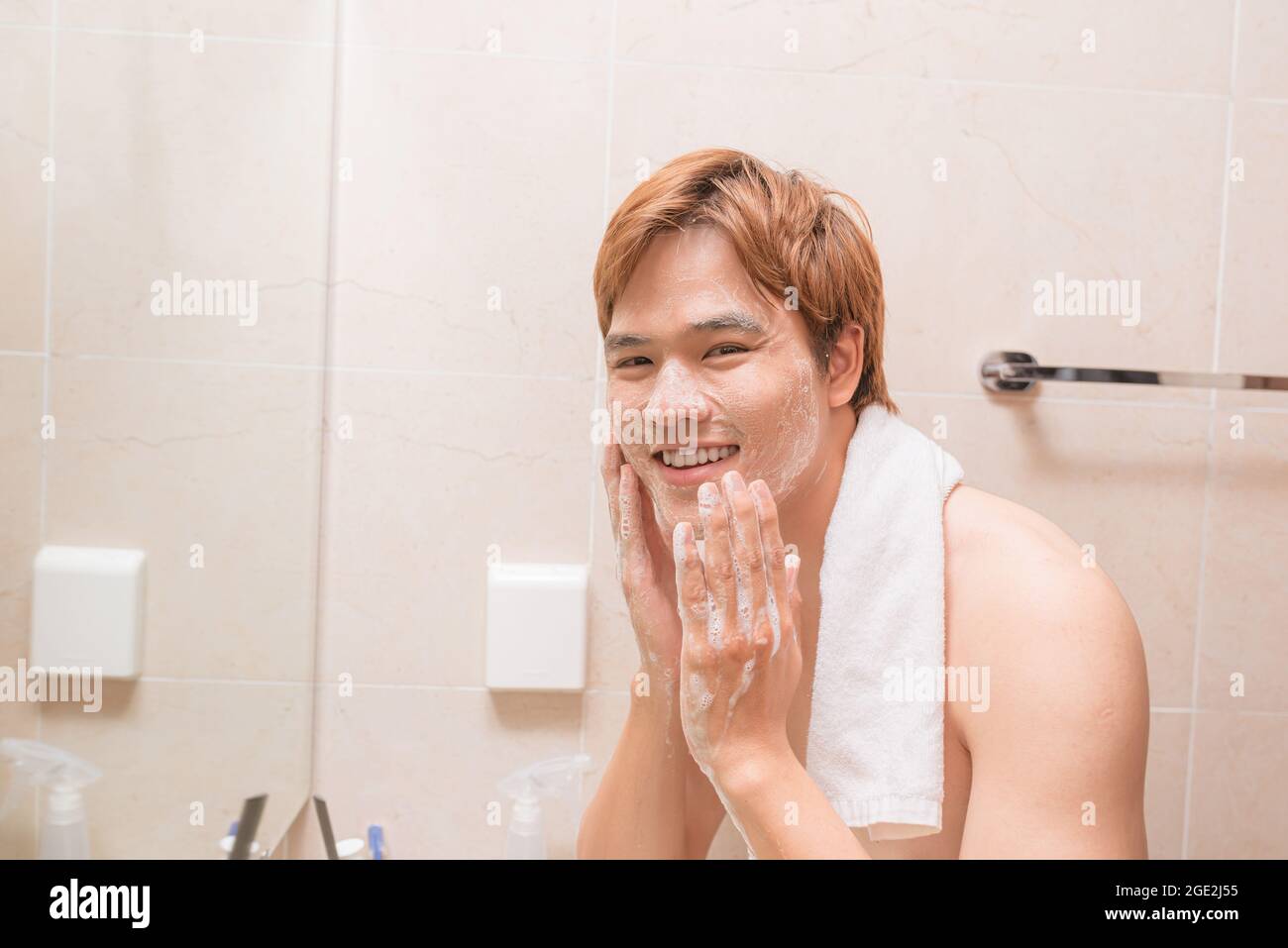 Porträt eines attraktiven jungen asiatischen Mannes waschen sein Gesicht im Badezimmer Stockfoto