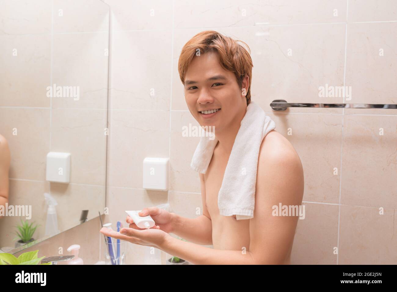 Porträt eines schönen lächelnden gesunden Mannes, der Schaum zum Waschen auf sein Gesicht aufschäumt. Stockfoto